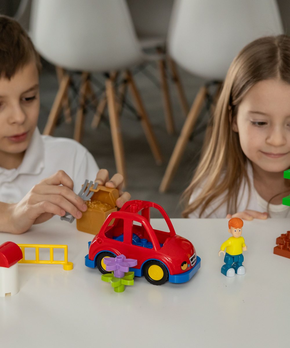 Two children playing together with colorful construction toys at a table